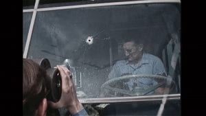 driver in bus with bullet hole in the windshield